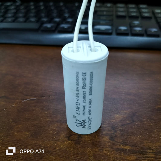Syscap 3MFD 250 VAC Running Capacitor electrical component with white wires on wooden surface