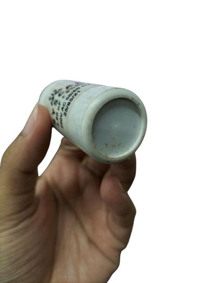 Hand holding a SYSCAP motor capacitor 250V AC showcasing its cylindrical design and printed specifications