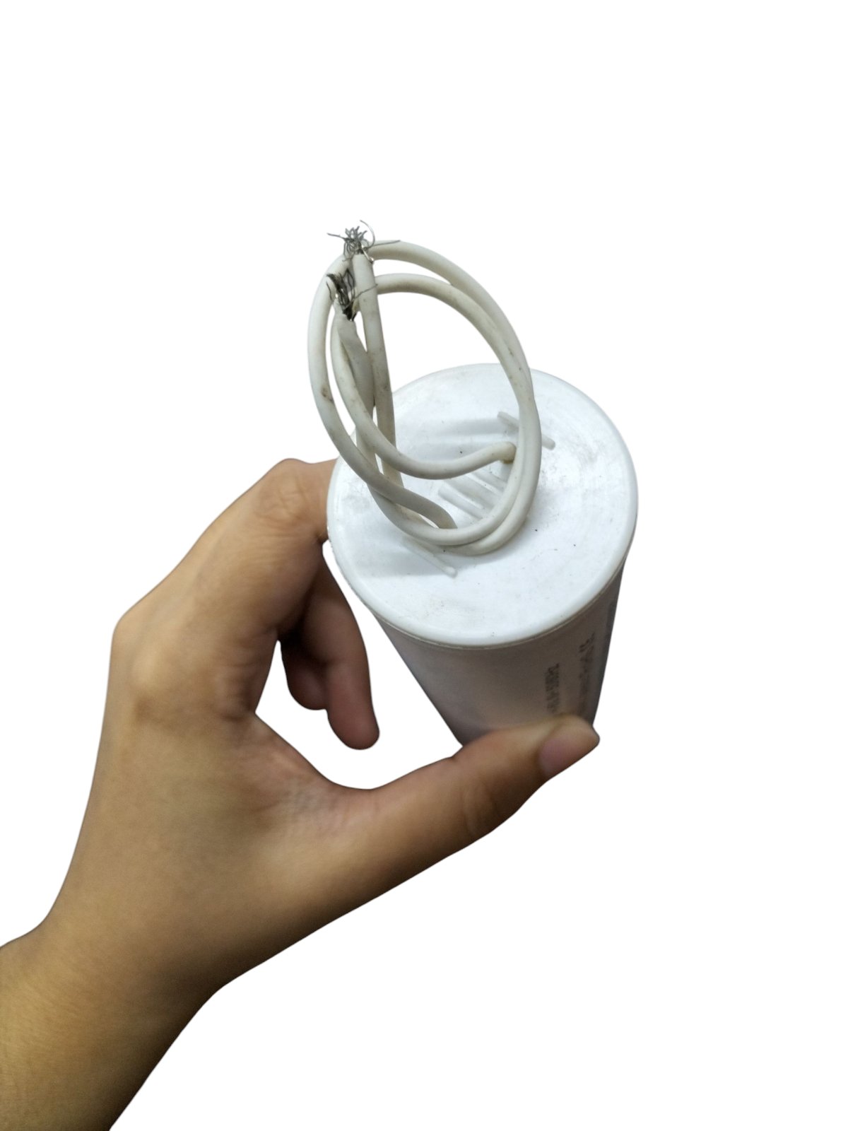Hand holding a motor running capacitor 25uF 600V with attached wires for electrical applications