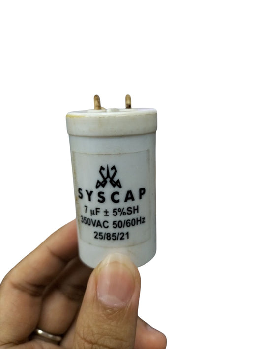 Syscap motor running capacitor 7.0MFD held in hand with white cylindrical body and electrical terminals